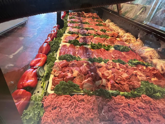Butcher display case filled with fresh halal steaks, stew cubes and ground beef