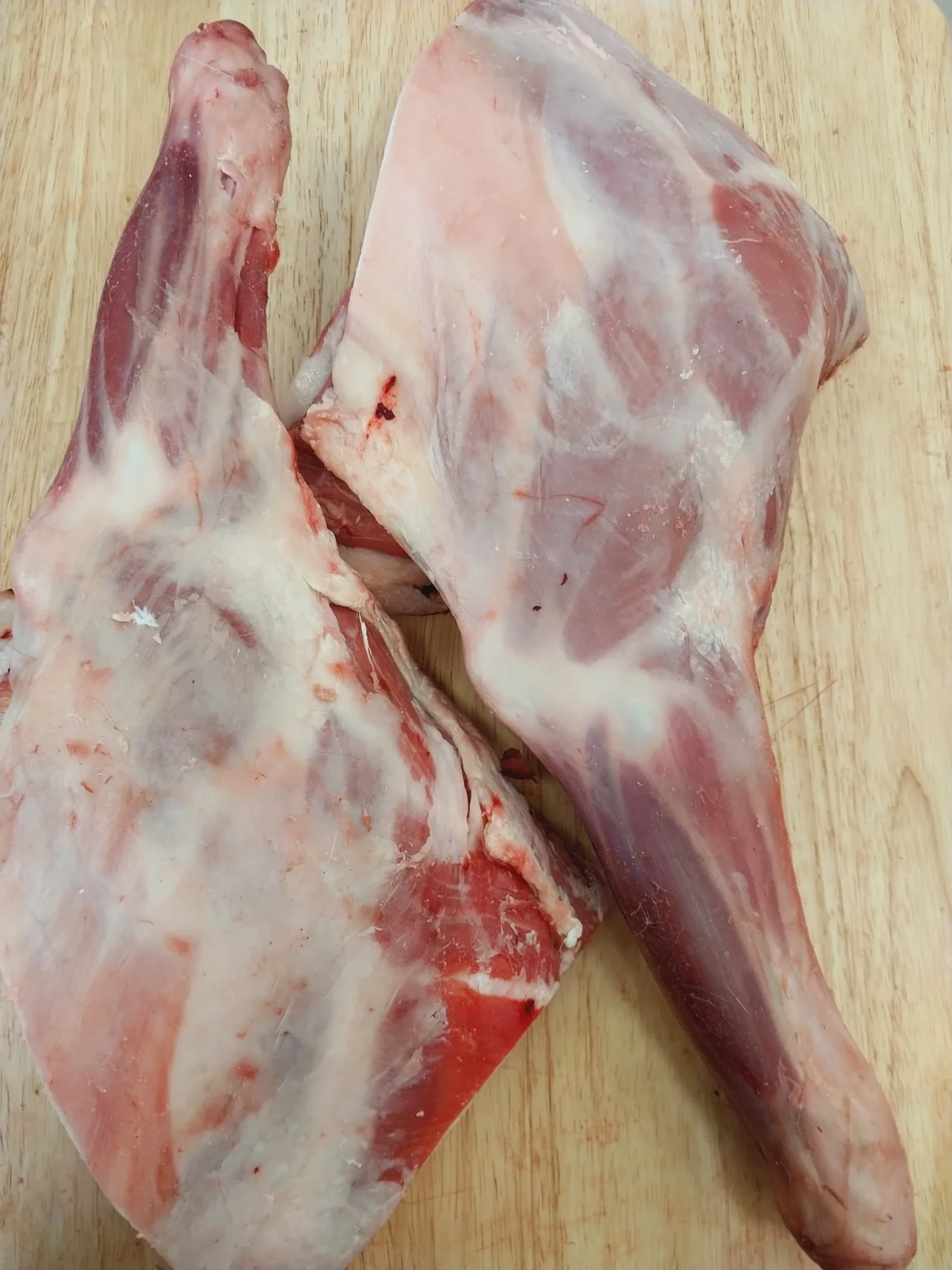 Fresh halal goat shoulders on a wooden board