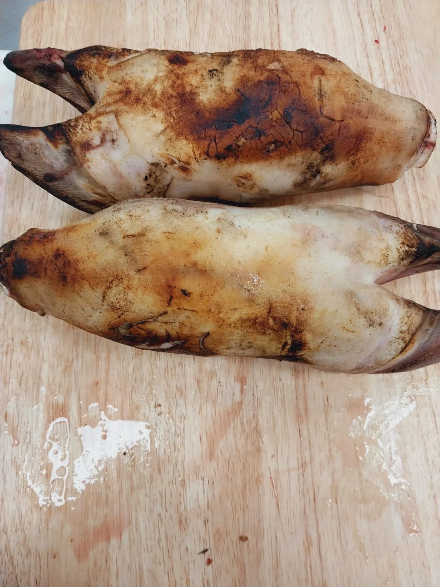 Singed brown halal beef feet on a wooden board