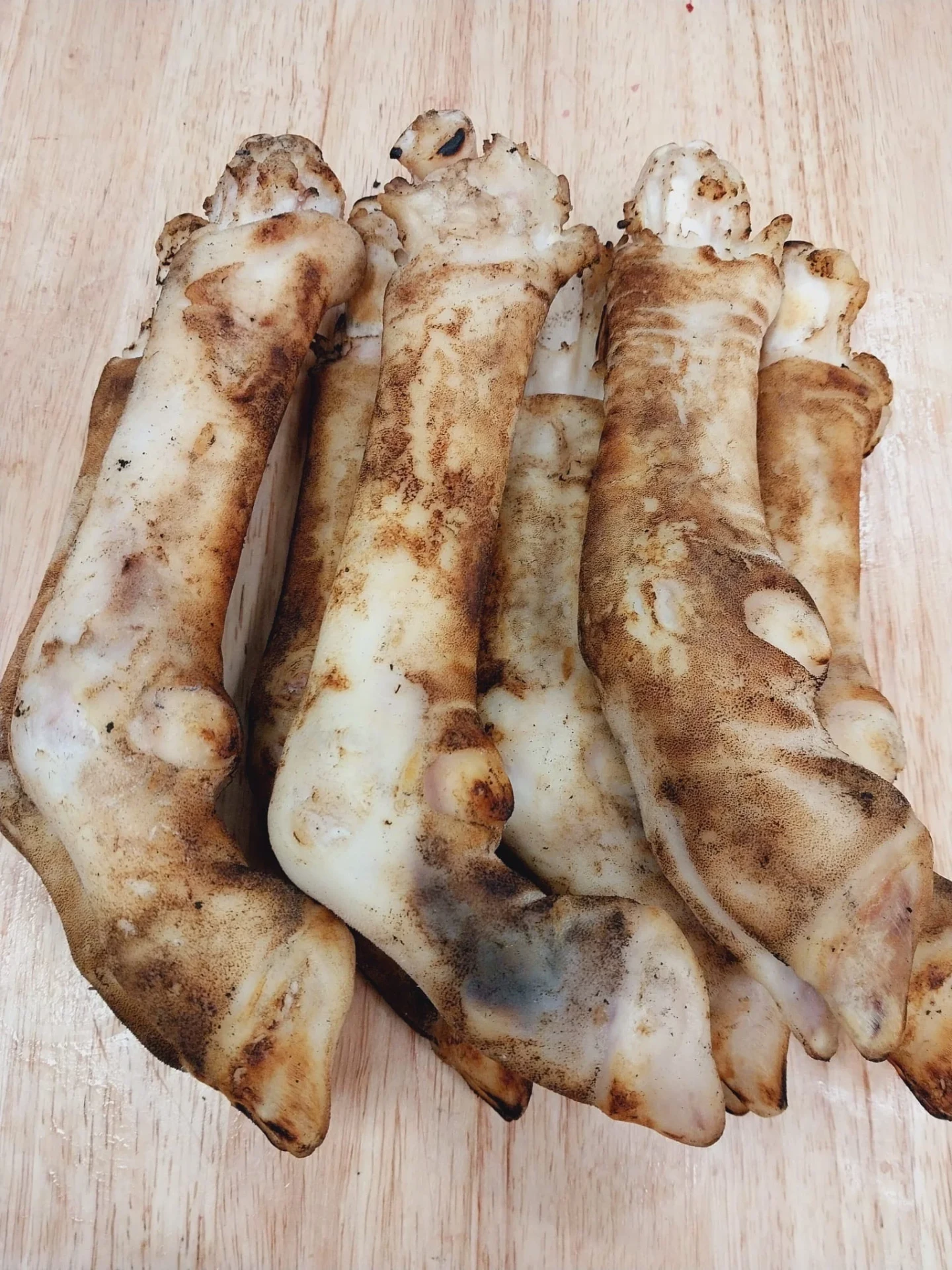 Singed brown halal goat feet on a wooden cutting board