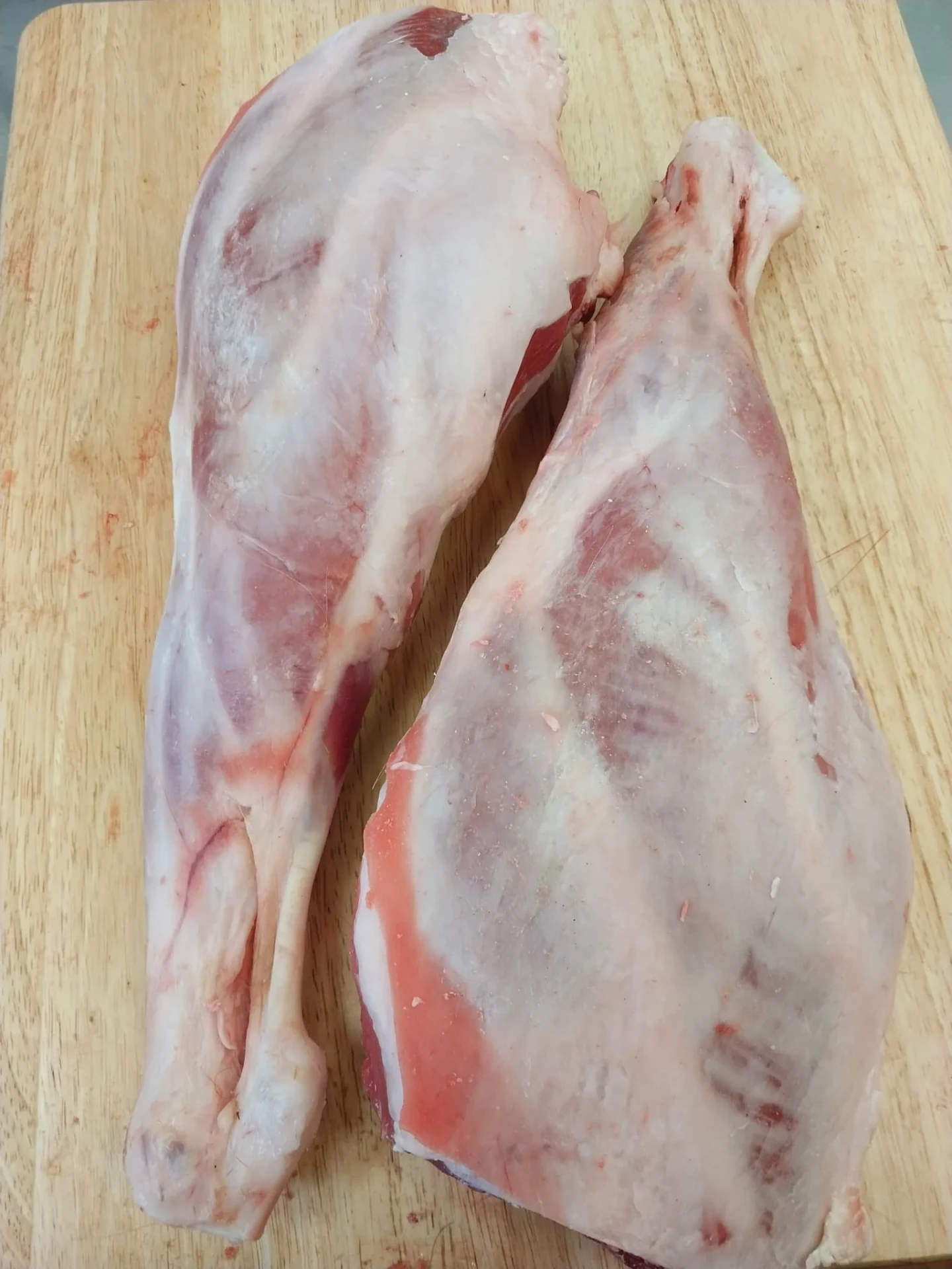 Two whole halal goat legs on a wooden board