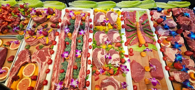 Halal meat platters of chops, steaks and ribs garnished with strawberries, citrus and orchids
