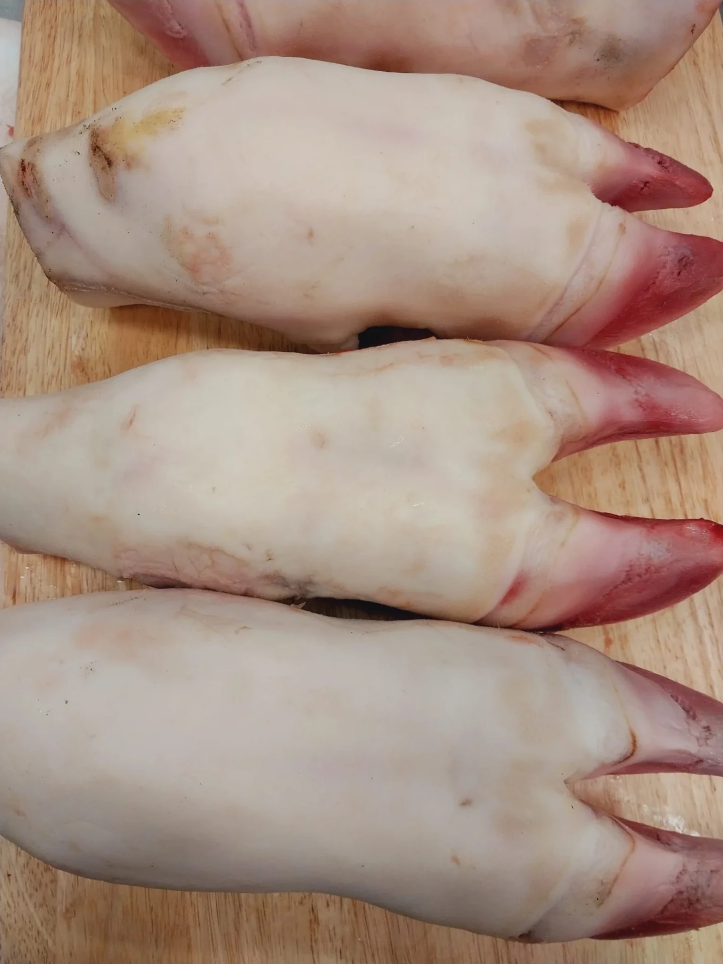 Fresh cleaned halal beef feet on a wooden cutting board